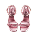 Elegant metallic pink ankle cross sandals with braided front strap and stiletto heel, perfect for evening wear.