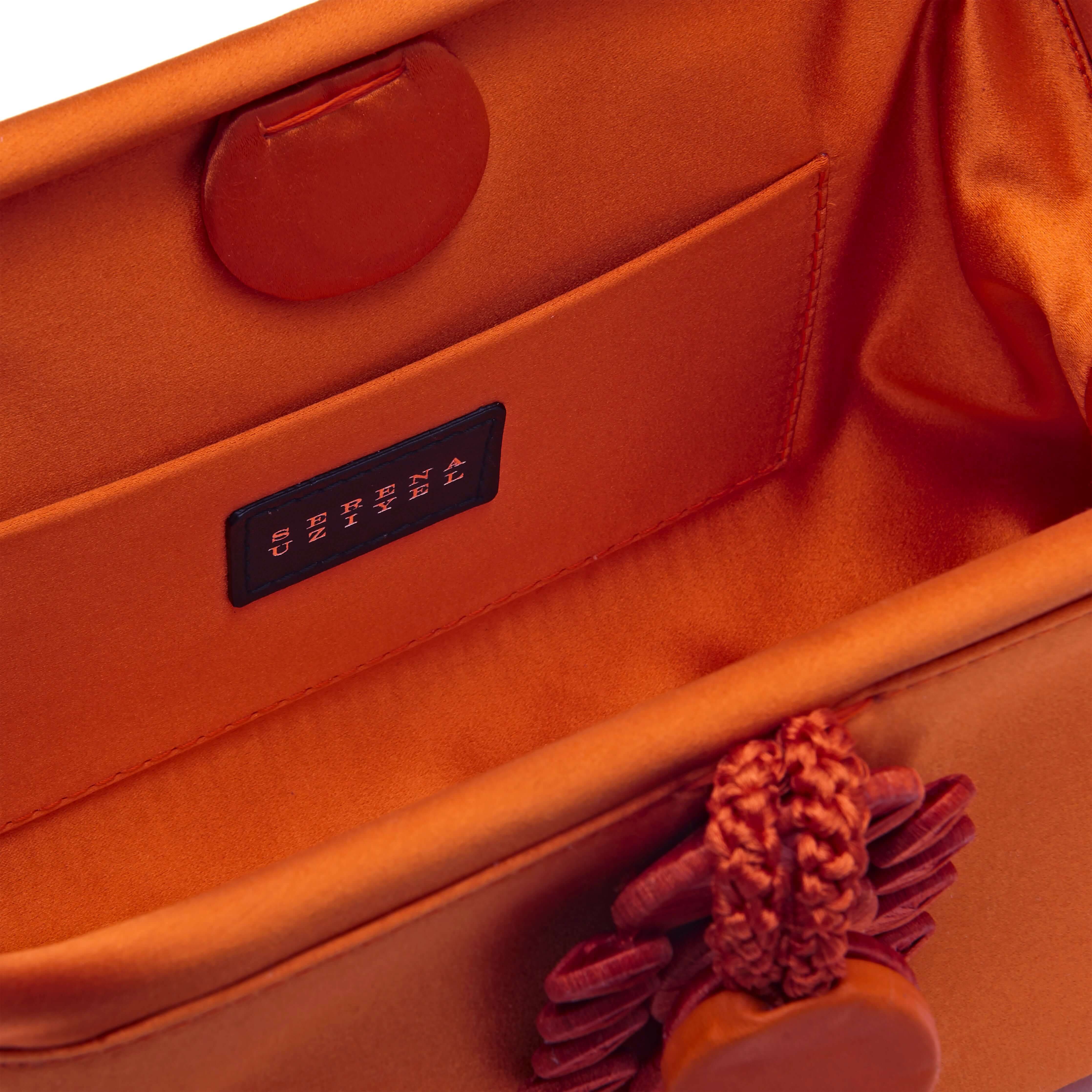 Interior view of Alessa Tangerine Pouch Bag, showcasing silk-satin fabric and intricate knotted coin design.