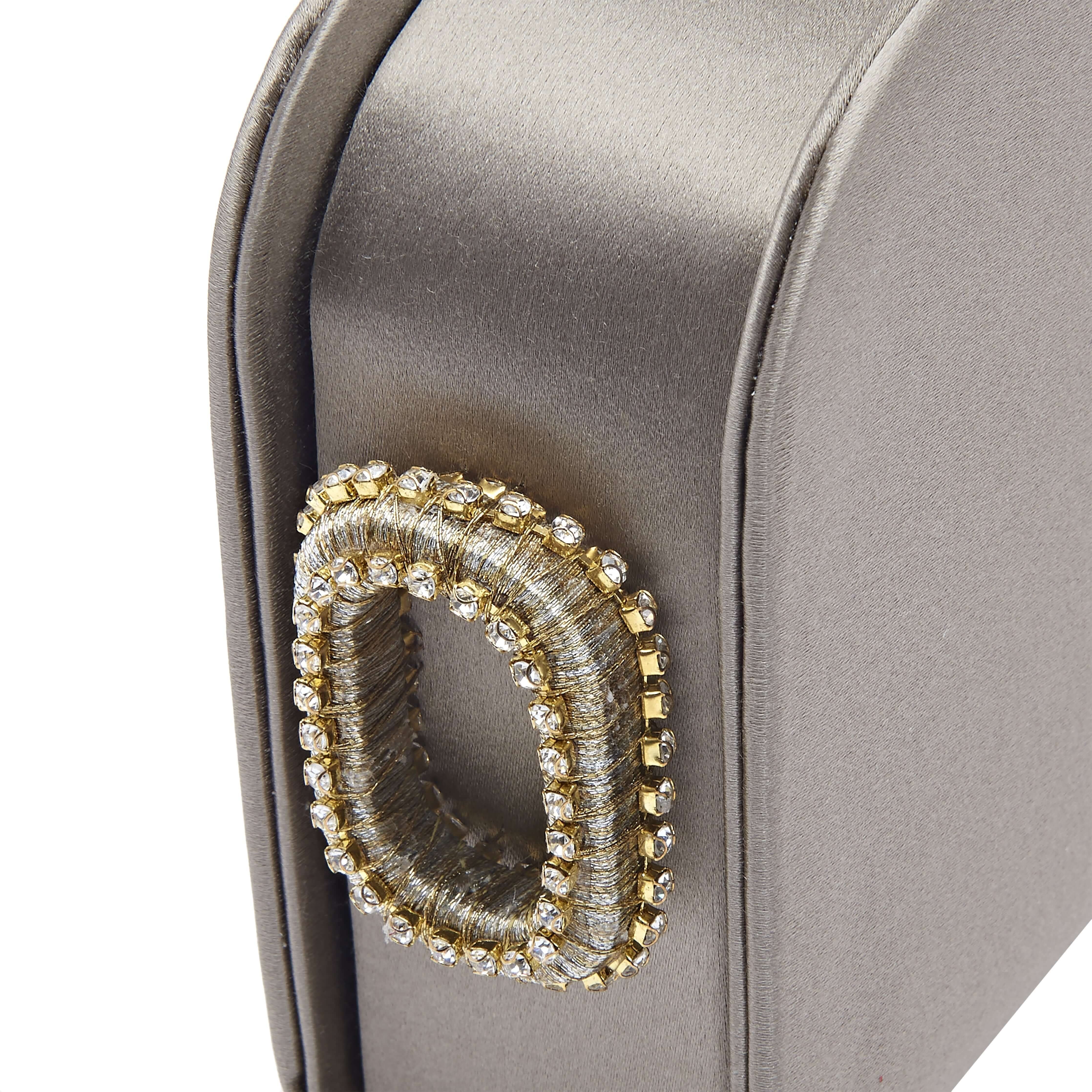 Close-up of the Catena Electrum One glam two-sided clutch showcasing its elegant bijoux accent and refined silk satin texture.