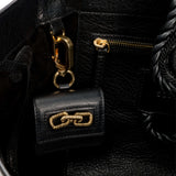 Interior view of a black leather handbag showcasing a gold chain accent and zipper pocket.