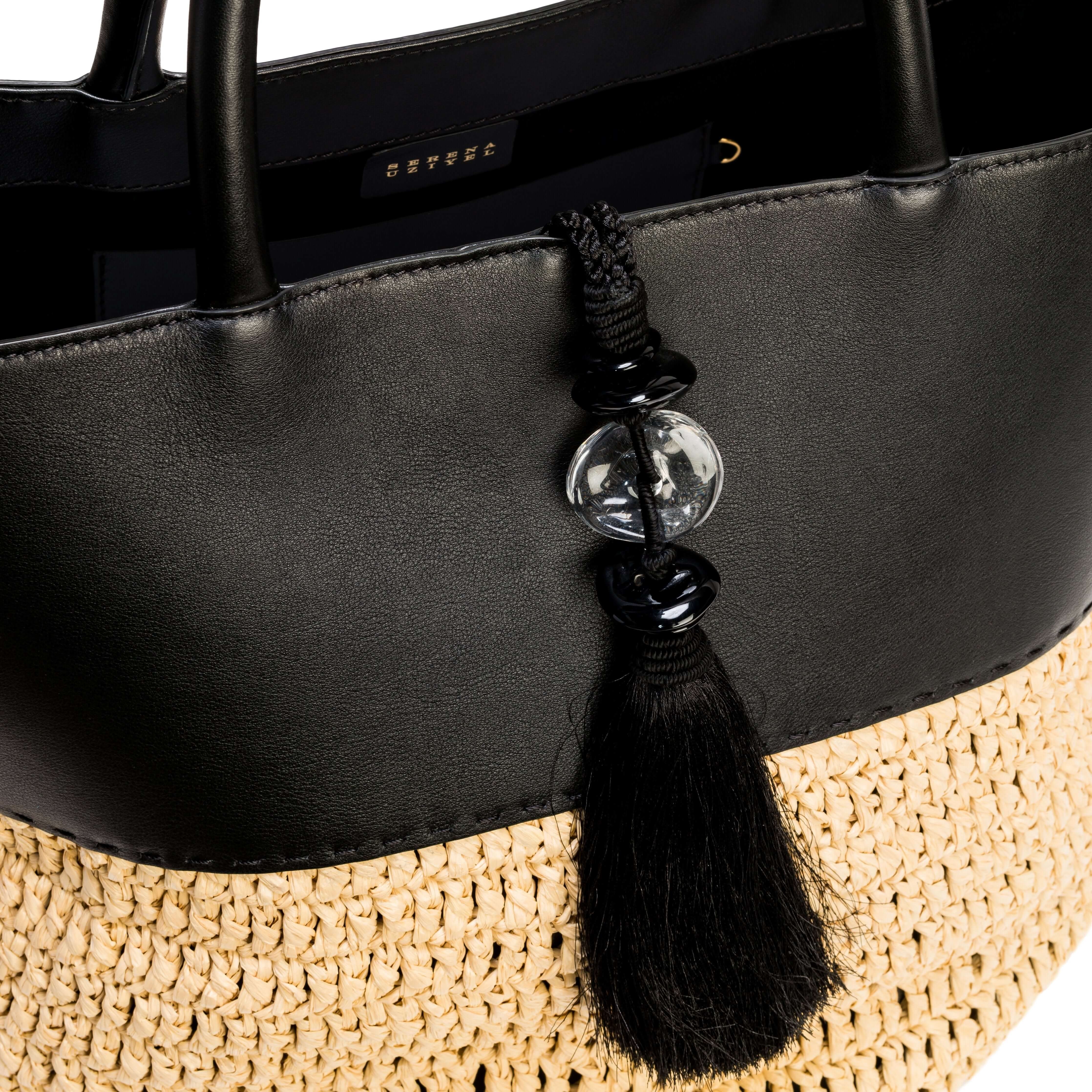 Close-up of Melita Black Large Tote Bag, featuring elegant black leather and woven straw details with decorative tassel.