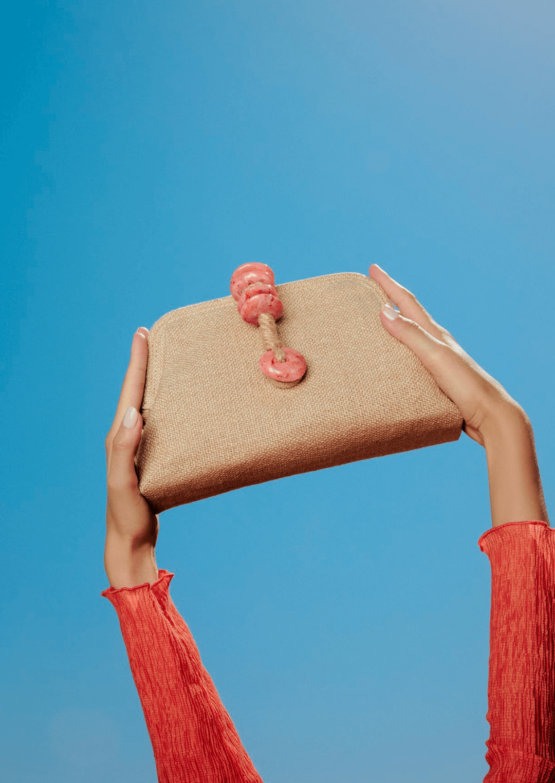 Petra Coral Pouch Bag featuring a jute rope clasp and natural stones against a clear blue sky.