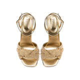 Rhea Gold Ankle Cross Sandal featuring metallic leather and braided crochet strap, elegant stiletto heel.
