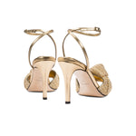 Elegant Rhea Gold Ankle Cross Sandal with stiletto heel and intricate braided crochet detail.