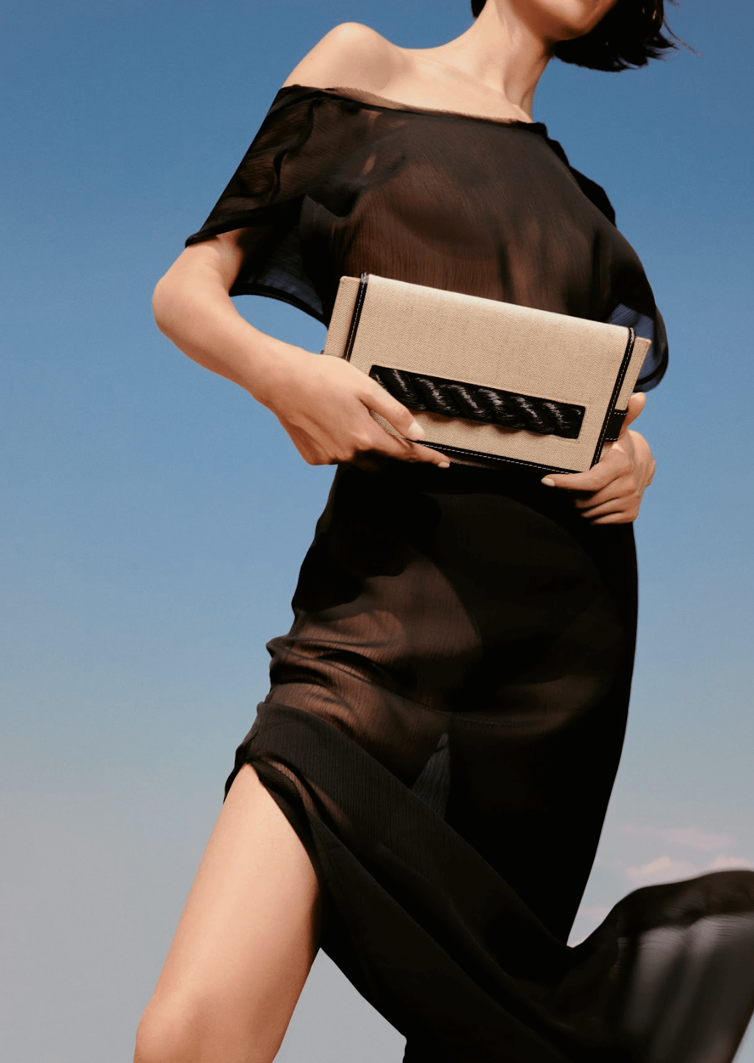 Model showcasing Thory Black Envelope Clutch against a clear sky, embodying sophistication and modern style.
