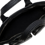 Close-up of a black leather handbag with braided handle on a white background