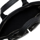 Close-up of a black leather handbag with braided handle on a white background