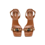 Delphine Camello Mid-Heel Ankle Cross Sandal with stylish design and elegant detailing in brown and beige.
