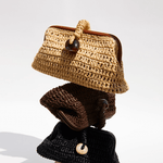 Stack of three artisan-crafted pouch bags made from natural raffia in umber tones.