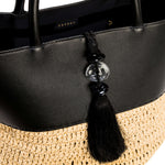 Close-up of Melita Black Large Tote Bag, featuring elegant black leather and woven straw details with decorative tassel.