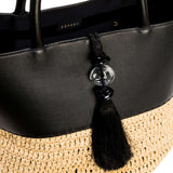 Close-up of Melita Black Large Tote Bag, featuring elegant black leather and woven straw details with decorative tassel.