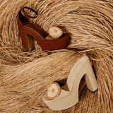 Narcissa Sand Platform Sandals in tan and beige suede with floral accents, set against a textured hay background.