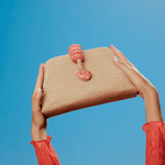 Petra Coral Pouch Bag featuring a jute rope clasp and natural stones against a clear blue sky.