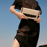 Model showcasing Thory Black Envelope Clutch against a clear sky, embodying sophistication and modern style.