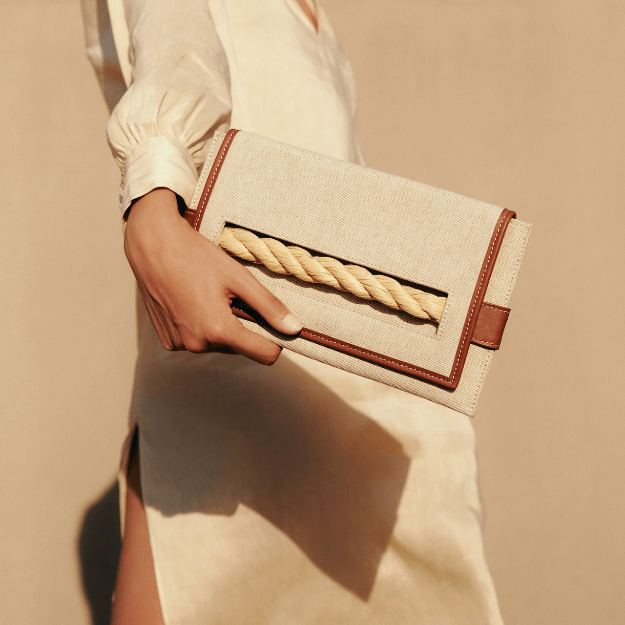 Thory Camello Envelope Clutch in natural canvas with camello leather trim, featuring a twisted raffia closure.